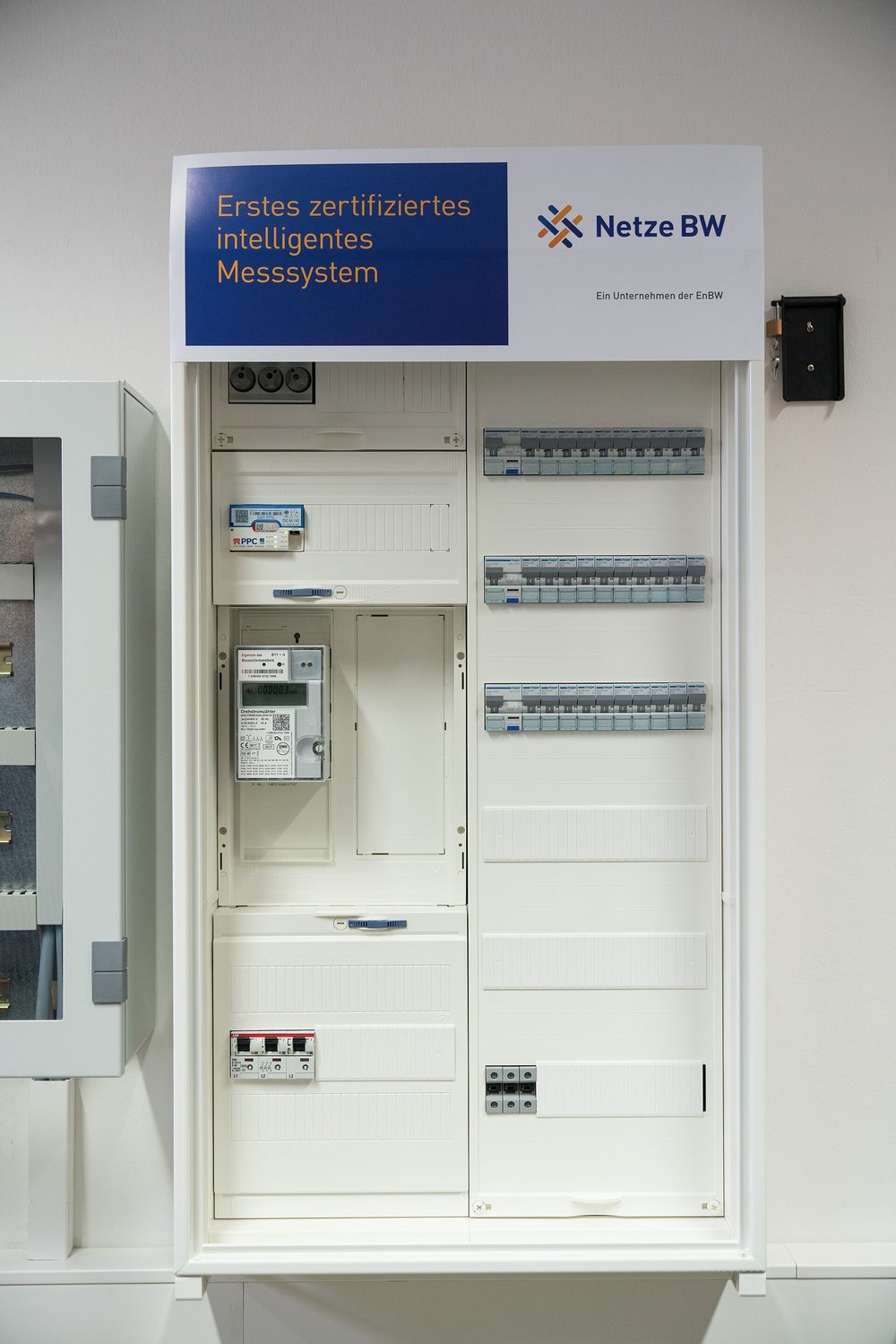 Vorführ-Zählerschrank der Netze BW: im oberen Feld ein Smart-Meter-Gateway, darunter im Zählerfeld eine moderne Messeinrichtung mit Display, rechts ein Verteilerfeld mit Leitungsschutzschaltern