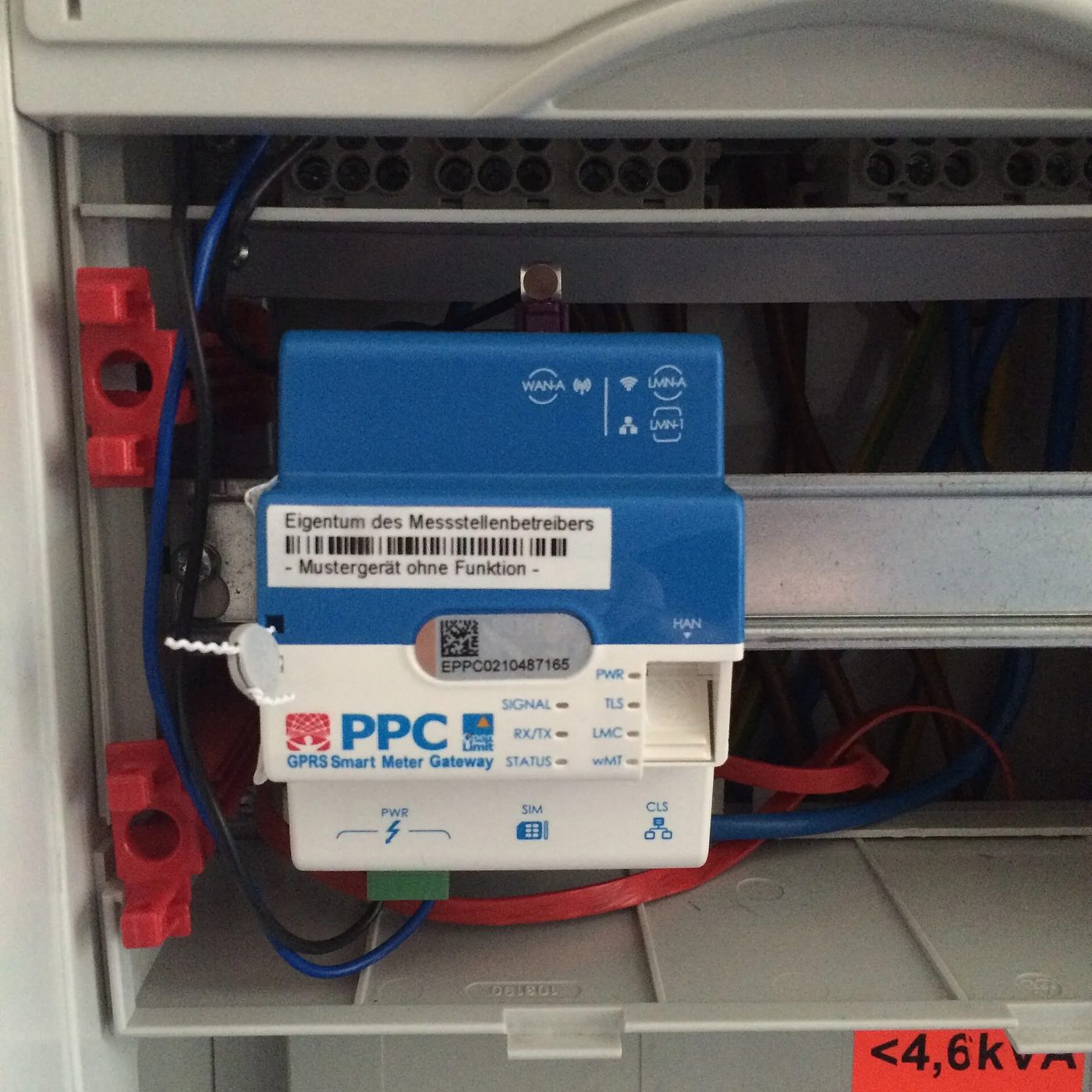 Smart-Meter-Gateway in einem Zählerschrank, blaues Gehäuse mit weißer Front, Beschriftung PPC GPRS Smart Meter Gateway, darauf ein Aufkleber „Eigentum des Messstellenbetreibers – Mustergerät ohne Funktion“, Statusleuchten, HAN-Buchse und eine weiße Kunststoffplombe